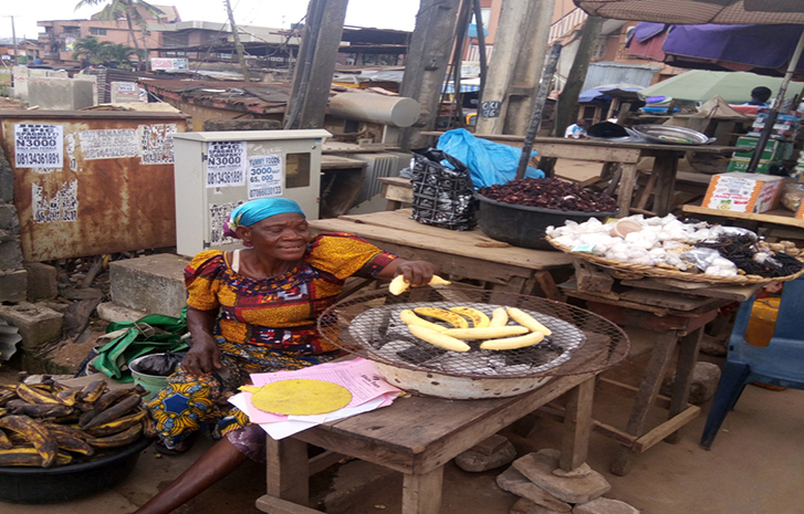A woman turns unfenced transformer to stand for roasting plantain at Oki junction, Iyana-Ipaja, Lagos, October 26, 2017